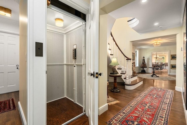 hallway with stairway, wood finished floors, crown molding, a chandelier, and baseboards