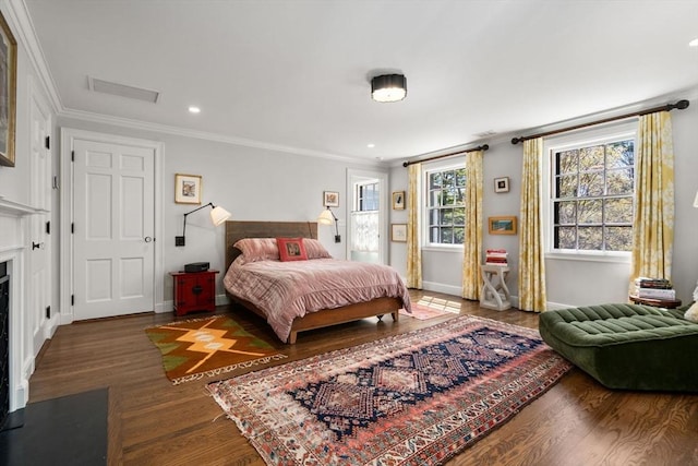 bedroom with wood finished floors, crown molding, a fireplace with flush hearth, baseboards, and recessed lighting