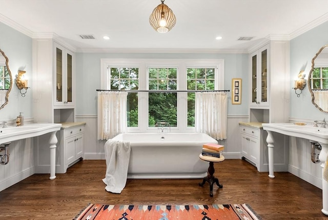 full bath with a freestanding bath, crown molding, wood finished floors, recessed lighting, and a decorative wall