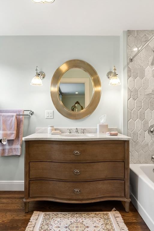 bathroom featuring wood finished floors, vanity, bathtub / shower combination, and baseboards