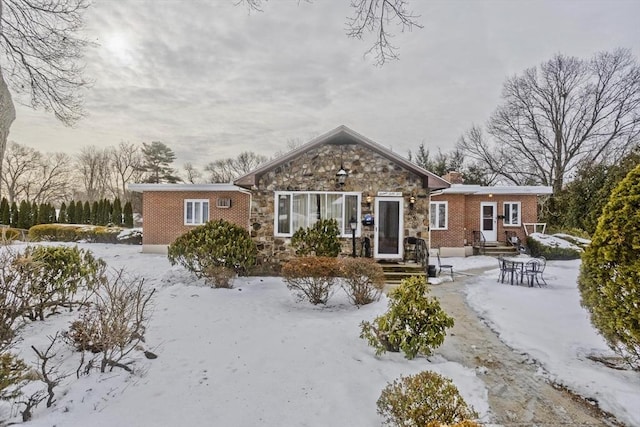 snow covered property featuring stone siding and brick siding