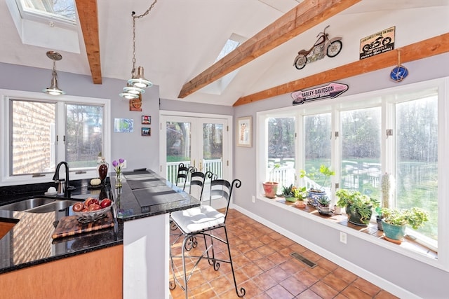 kitchen with lofted ceiling with beams, a healthy amount of sunlight, and decorative light fixtures