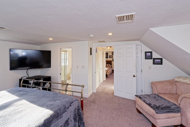 bedroom with a textured ceiling, light carpet, connected bathroom, and vaulted ceiling