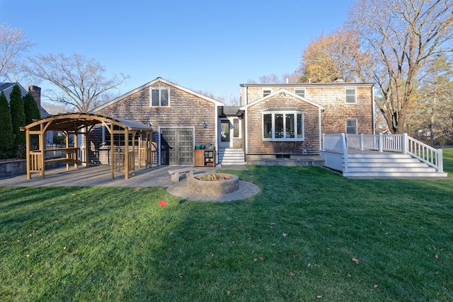 back of property with a lawn, a fire pit, and a deck