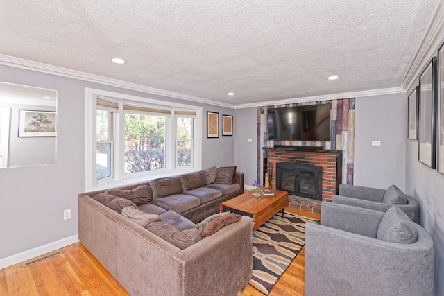 living room featuring a brick fireplace, light hardwood / wood-style floors, a textured ceiling, and ornamental molding