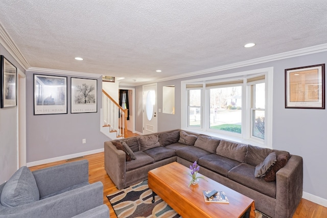 living room featuring a textured ceiling, light wood-type flooring, and ornamental molding