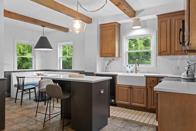 181 Lowell St, Andover, MA 01810 - kitchen with a sink, black dishwasher, beam ceiling, a breakfast bar, and decorative backsplash