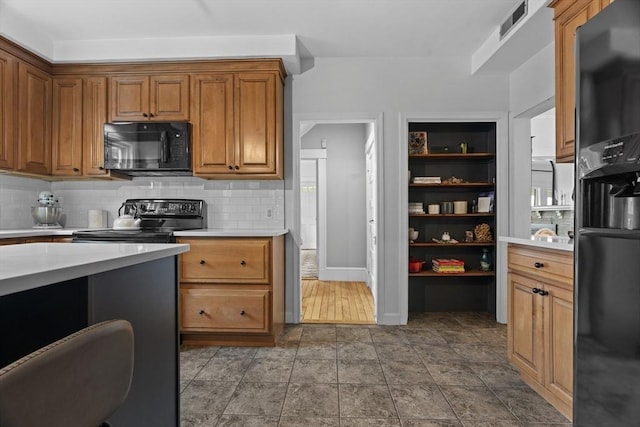 181 Lowell St, Andover, MA 01810 - kitchen with black appliances, light countertops, decorative backsplash, brown cabinets, and baseboards