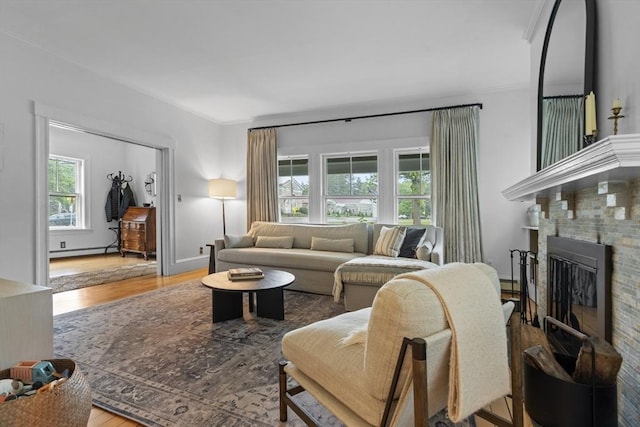 181 Lowell St, Andover, MA 01810 - living area featuring plenty of natural light, wood finished floors, a brick fireplace, a baseboard heating unit, and ornamental molding