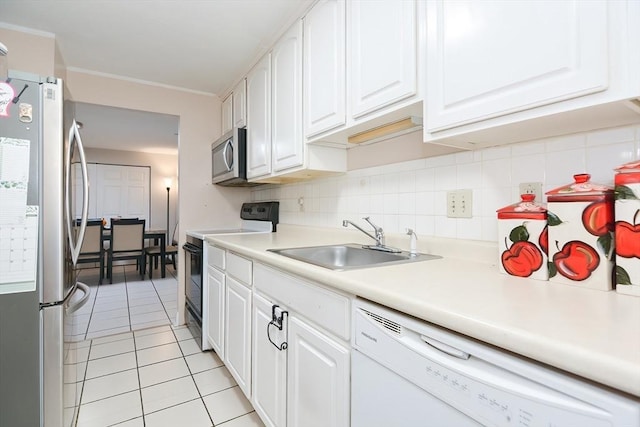kitchen with appliances with stainless steel finishes, light tile patterned floors, white cabinetry, and a sink