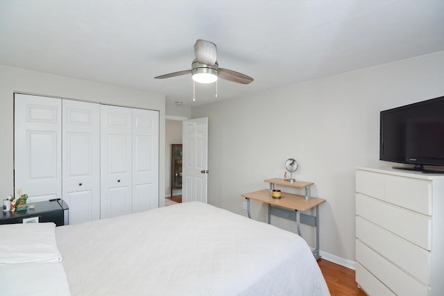 bedroom featuring wood finished floors, ceiling fan, baseboards, and a closet