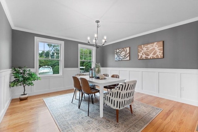 dining area featuring ornamental molding, light hardwood / wood-style flooring, and a notable chandelier