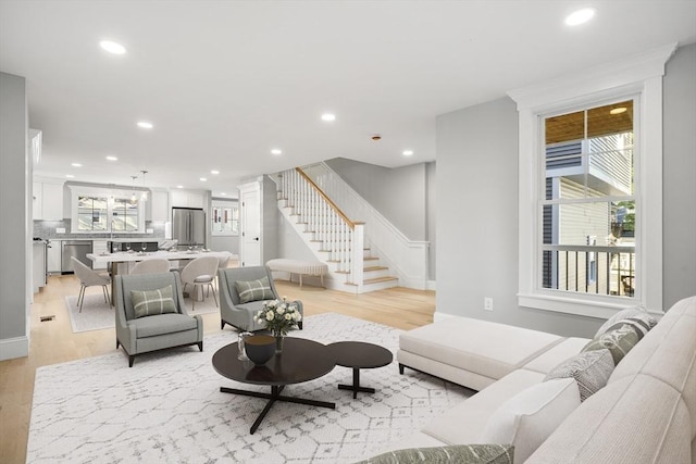 living area with recessed lighting, light wood finished floors, and stairs