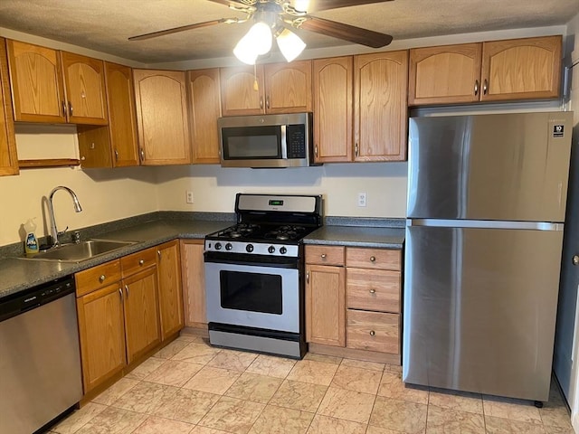 kitchen featuring dark countertops, a ceiling fan, stainless steel appliances, and a sink