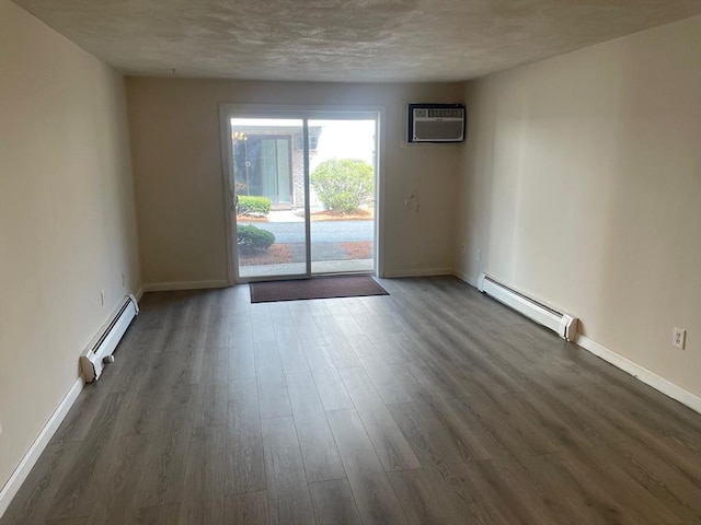 spare room with a baseboard heating unit, baseboards, dark wood-style floors, and a wall mounted air conditioner