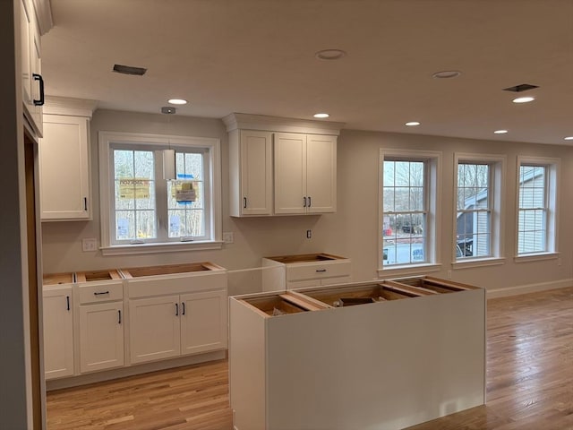 kitchen with white cabinetry, a center island, and light hardwood / wood-style flooring