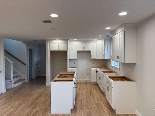 kitchen featuring a center island, white cabinets, and light wood-type flooring