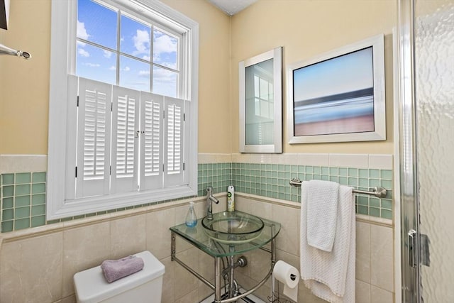 bathroom with toilet, tile walls, and sink