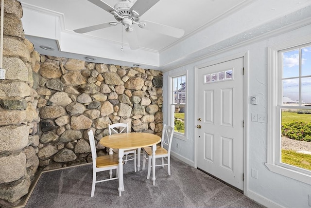 carpeted dining area with ceiling fan, a wealth of natural light, a tray ceiling, and ornamental molding