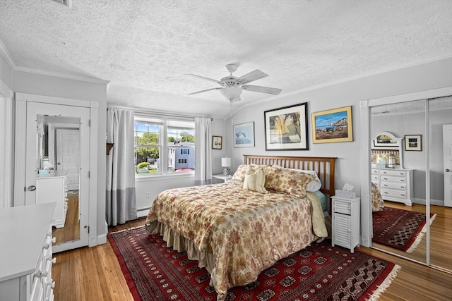 bedroom with ceiling fan, light hardwood / wood-style floors, ornamental molding, a textured ceiling, and baseboard heating