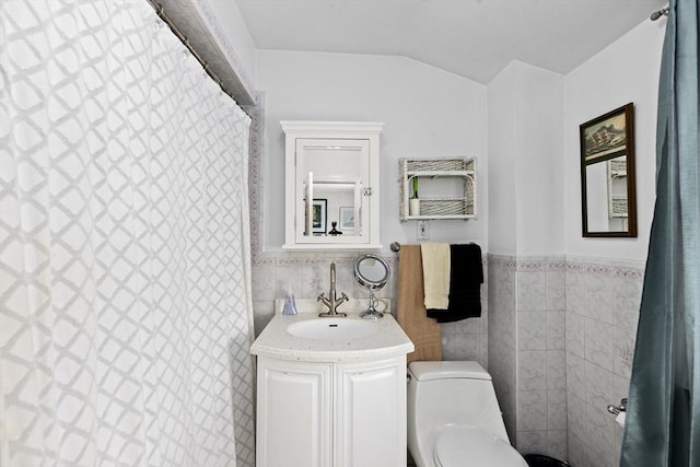 bathroom featuring toilet, vanity, tile walls, and vaulted ceiling