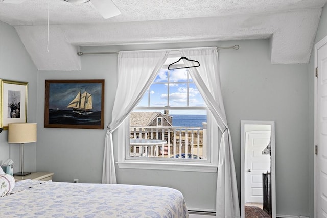 bedroom with ceiling fan, a water view, vaulted ceiling, and a baseboard heating unit