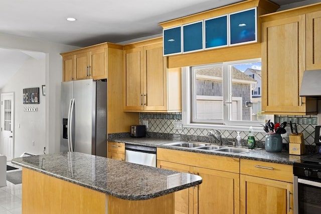 kitchen featuring stainless steel appliances, tasteful backsplash, sink, dark stone countertops, and a center island