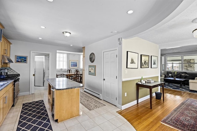 kitchen featuring light tile patterned floors, a healthy amount of sunlight, a baseboard radiator, and a center island