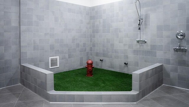 bathroom featuring a tile shower and tile patterned flooring