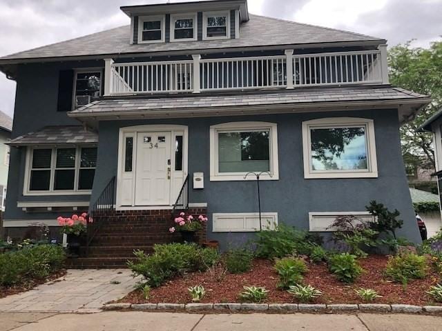 34 Arborway, Boston, MA 02130 - view of front of property with a balcony, entry steps, stucco siding, and a shingled roof