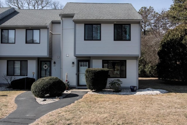 view of front facade featuring a front yard and a shingled roof