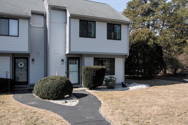 view of front of home featuring a front lawn and a shingled roof