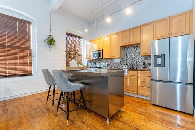 kitchen featuring appliances with stainless steel finishes, a kitchen breakfast bar, and light hardwood / wood-style floors