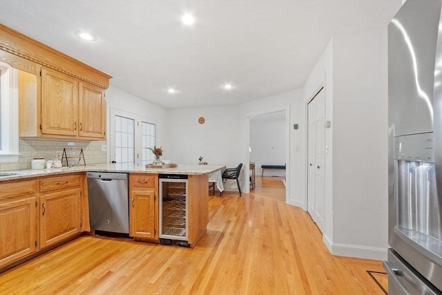 kitchen featuring beverage cooler, stainless steel appliances, light wood-type flooring, a peninsula, and recessed lighting