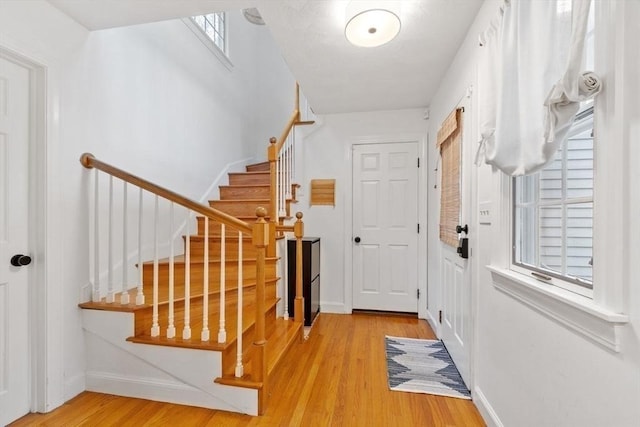 entrance foyer with wood finished floors, baseboards, and stairway