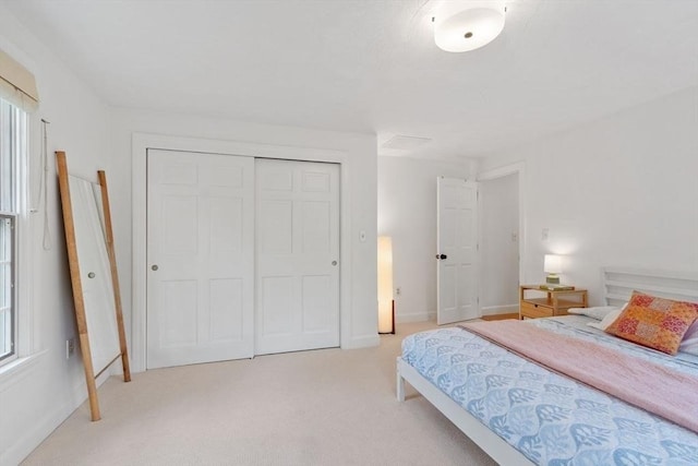 bedroom with a closet, light carpet, and baseboards