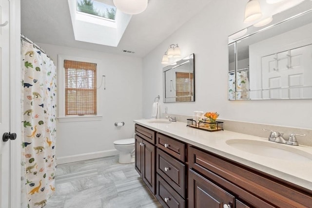 bathroom featuring a skylight, toilet, double vanity, marble finish floors, and a shower with shower curtain