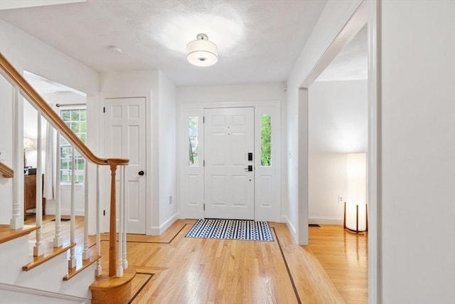 entryway featuring stairway, light wood-style flooring, and baseboards