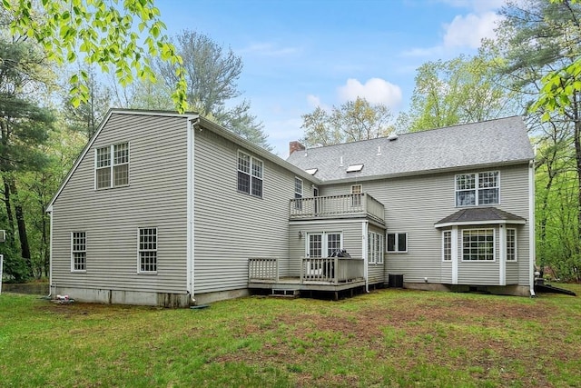 rear view of house with a balcony, a lawn, a deck, and a chimney