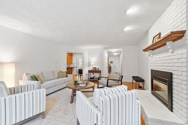 living area with a brick fireplace, light wood-style flooring, and recessed lighting