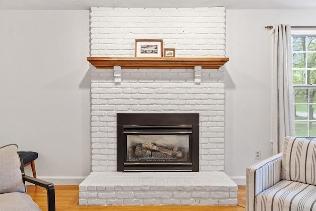 detailed view of wood finished floors, baseboards, and a brick fireplace