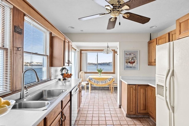 kitchen with white refrigerator with ice dispenser, a water view, a sink, light countertops, and pendant lighting