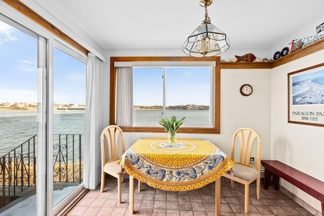 dining space featuring a healthy amount of sunlight, a water view, and an inviting chandelier