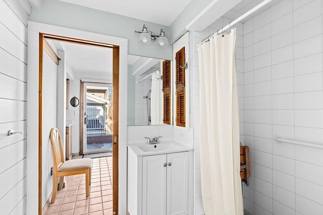 bathroom with tile walls, tile patterned flooring, vanity, and curtained shower