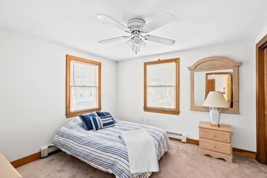 bedroom featuring multiple windows, light carpet, and baseboard heating