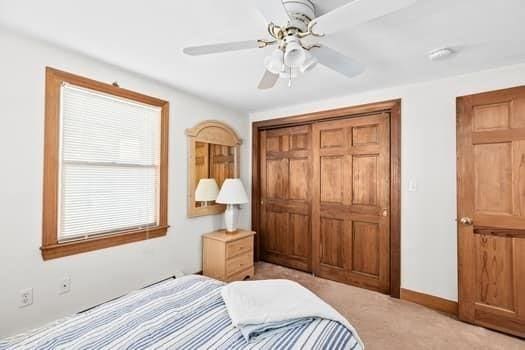 bedroom with ceiling fan, baseboards, a closet, and light colored carpet