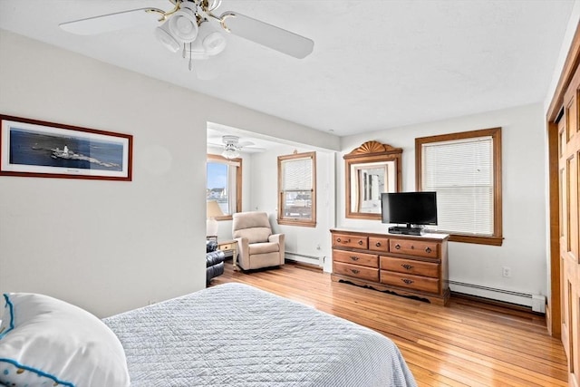 bedroom with light wood-type flooring, a baseboard radiator, and a ceiling fan