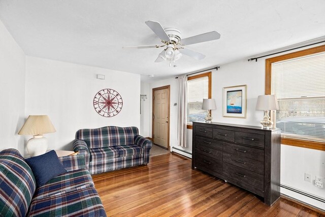 living room featuring a baseboard heating unit, wood finished floors, and a ceiling fan