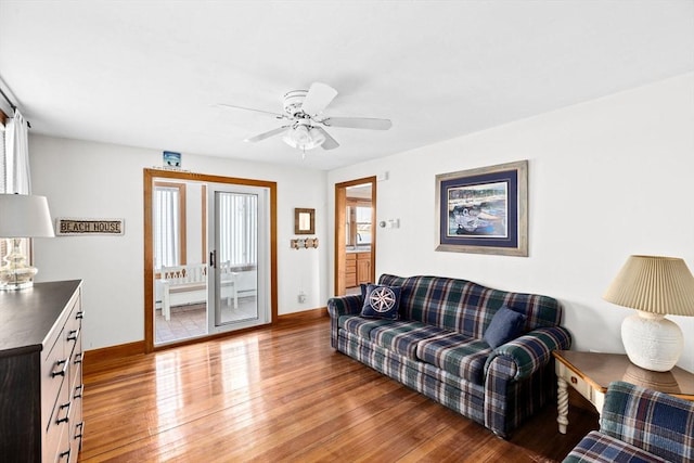 living room with wood finished floors, a ceiling fan, and baseboards