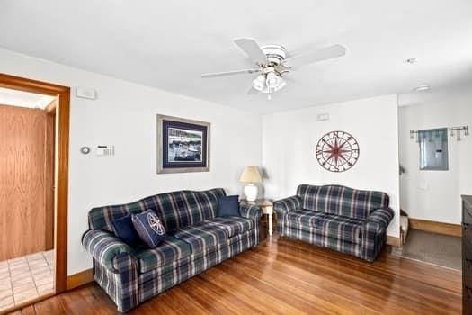 living room featuring ceiling fan, baseboards, and wood finished floors